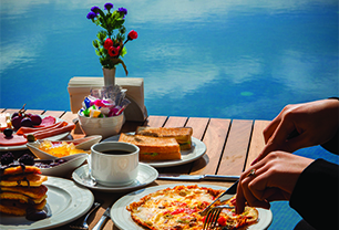 woman-eats-omelet-with-vegetables-pancakes-food-with-chocolate-cake-wooden-table.Featured image